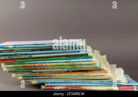 Stack of old school exercise books on a gray background. Random thin notebooks are stacked on top of each other. Close-up. Selective focus. Stock Photo