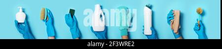 Hands in gloves holding detergent bottles on blue background. Banner with copy space. Chemical cleaning products, household chemicals, brushes and Stock Photo