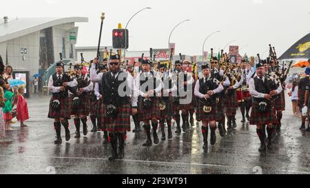 A Scottish pipe and drum band parading down the street in heavy rain. Hamilton, New Zealand Stock Photo