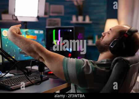 Happy professional player streaming esport tournament using microphone and  headphones, enjoying a multiplayer game. Competitive gamer playing online  video game at home. Neon color. Cyber sport concept Stock Photo