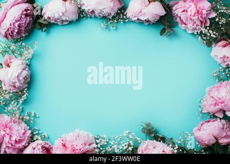 Floral pattern, frame made of pink peonies, white gypsophila flowers, eucalyptus on blue background. Flat lay, top view. Copy space. Wedding, birthday Stock Photo
