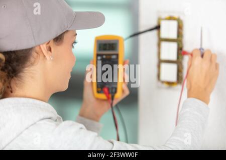 rear-view of female electrician using a multimeter Stock Photo