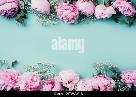 Creative frame pattern of pink peonies, gypsophila flowers, eucalyptus on blue background. Flat lay, top view. Floral composition. Wedding, birthday Stock Photo
