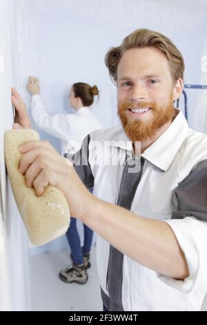 happy man polishing plastered walls with sponge Stock Photo
