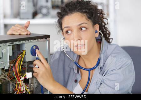 female technician using stethoscope for examines computer Stock Photo
