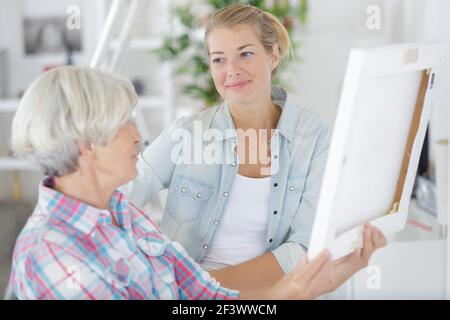 senior woman looks at photo in frame with daughter Stock Photo
