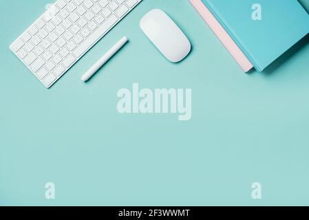 Home designer office workspace. White mouse, keyboard, notebook, pen on blue background. Top view. Copy space. Flat lay. Remote job, work. Feminine Stock Photo
