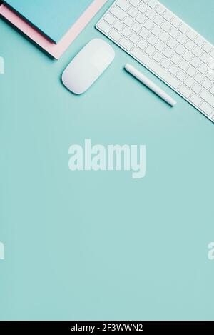 Home designer office workspace. White mouse, keyboard, notebook, pen on blue background. Top view. Copy space. Flat lay. Remote job, work. Feminine Stock Photo