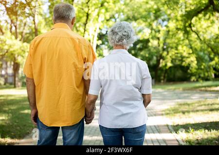 Old senior couple together walk through the park Stock Photo