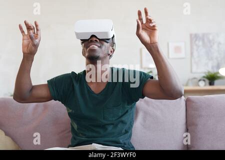 African young man using vr glasses and playing in new trends of technology on the sofa Stock Photo