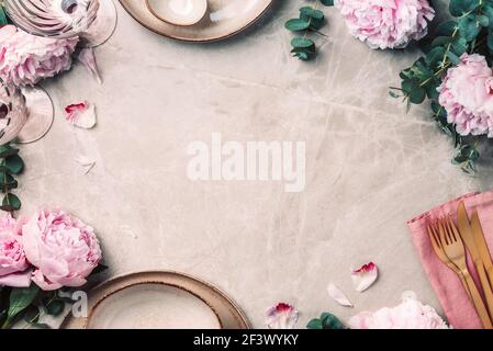 Flower arrangement on table served for festive dinner with copy space for your text, invitation. Greeting card. Top view. Peony, eucalyptus, plates Stock Photo