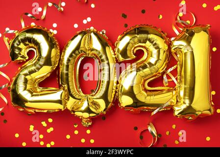 Golden foil balloons made numbers 2021 on red background with light bokehs. Happy new year celebration party. Greetings and congratulation concept Stock Photo