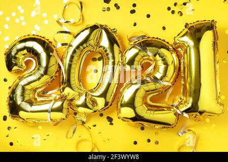 Golden foil balloons made numbers 2021 on yellow background with light bokehs. Happy new year celebration party. Greetings and congratulation concept Stock Photo