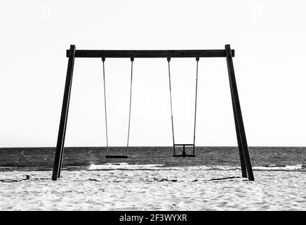Empty Wooden swing facing the sea in the morning in Alicante, Spain. Monochrome picture. Stock Photo