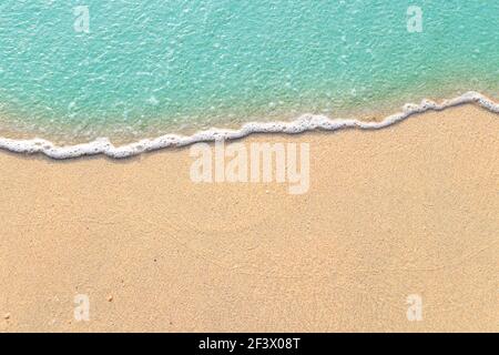 Soft waves with foam of blue ocean on the sandy beach Stock Photo