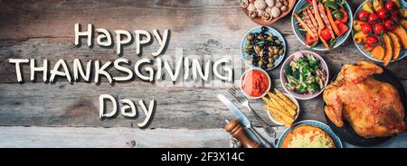 Roasted whole chicken or turkey, pumpkins, corn and harvest vegetables with kitchen knife and cutlery served around aged wooden cutting board on dark Stock Photo