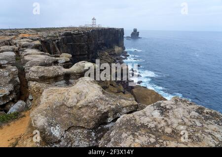 An ancient lighthouse on a huge cliff of Carvoeiro cape at sunrise in Peniche, Atlantic coast, Portugal Stock Photo