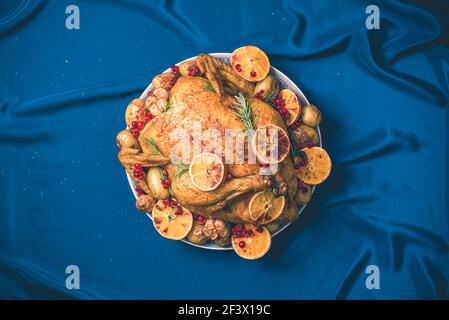 Roasted chicken with oranges, rosemary and cranberries on plate over concrete background. Traditional Thanksgiving or Friendsgiving holiday Stock Photo