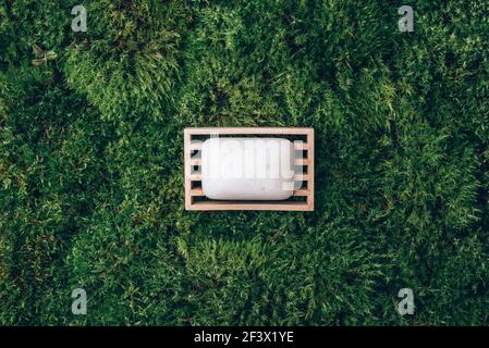 Handmade shampoo, soap bar on wooden dish over green moss texture. Copy space. Top view. Zero waste, eco friendly product, natural organic bathroom Stock Photo