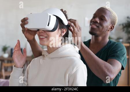 Man putting vr headset on woman she trying to play virtual reality game Stock Photo