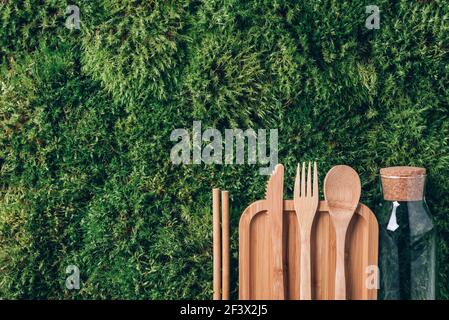 Glass bottle, wooden cutlery, bamboo food containers on green moss background. Top view. Copy space. Zero waste. Recycling concept. Takeaway food for Stock Photo