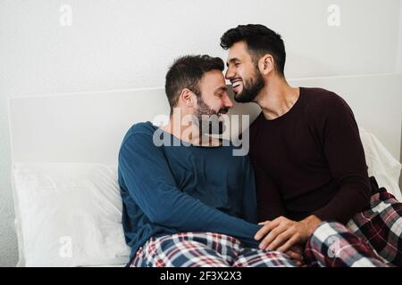 Young gay couple having tender moment in bed at home - Focus on faces Stock Photo