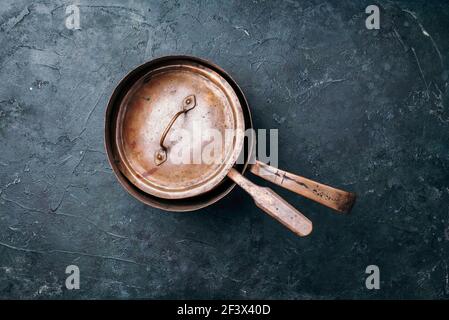 Old vintage copper pots on dark background. Kitchen utensils. Rustic pan. Top view, copy space for your text Stock Photo
