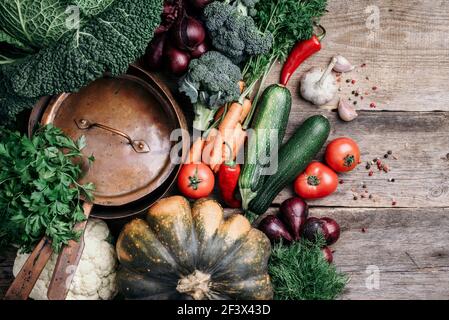 Healthy, clean food cooking and eating concept. Copper pan, colorful autumn vegetables on wooden background. Top view. Copy space. Vegetarian cooking Stock Photo