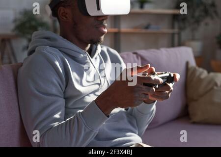 African American man in virtual reality headset playing interactive computer game indoors Stock Photo
