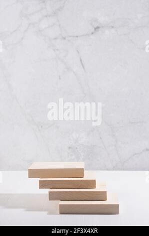 Wood podium of planks with sunlight and shadow for presentation and product display on white wood table and marble wall, vertical. Stock Photo
