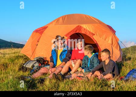 Family enjoys evening sun in front of a tent Stock Photo