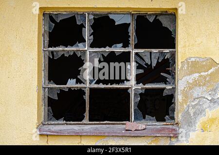 Old factory window with broken glass and rusty iron frame Stock Photo