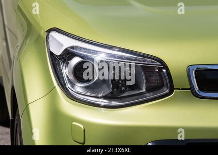 the right headlight of a new olive car close up Stock Photo