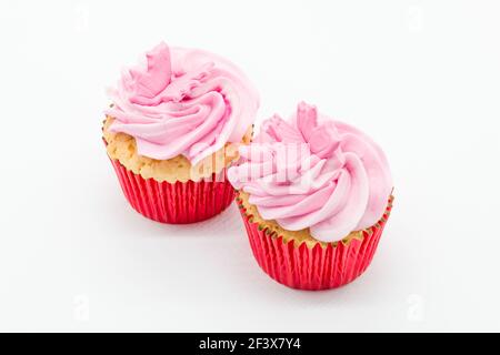 Easter cup cakes two in number with pink icing and red sponge casings on a white background. Stock Photo