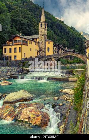 The alpine village of Fontainemore in the Lys Valley with its Roman bridge that crosses the alpine stream of the Lys. Aosta, Val d'Aosta, Italy Stock Photo