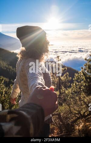 Portrait of happy young adult woman holding hand of her boyfriend while walking by mountain stream. Couple enjoying leisure in nature. Amazing mountai Stock Photo