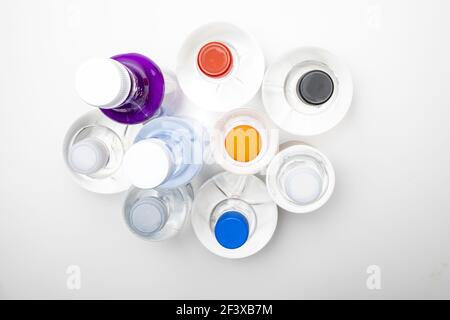 Background of transparent spherical water bottles with colored caps. Top view. Stock Photo