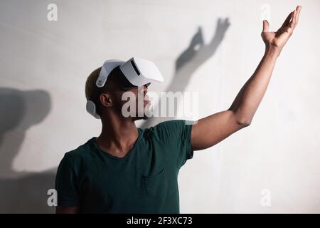 Portrait of African gamer in vr glasses gesturing standing against the white background Stock Photo