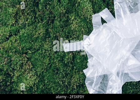 Pollution problem concept. Disposable plastic bags on green moss, grass background. Top view. Copy space. Environmental pollution problem. Garbage Stock Photo