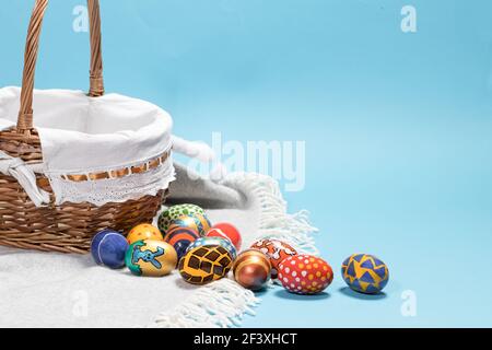 Delicate minimalist Easter photo - a wicker basket and painted eggs on a blue background copy space for text Stock Photo