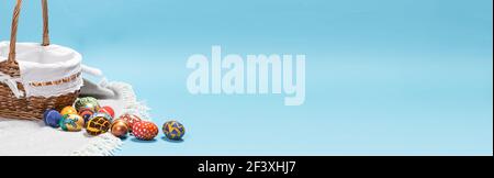 Delicate minimalist Easter photo - a wicker basket and painted eggs on a blue background copy space for text Stock Photo
