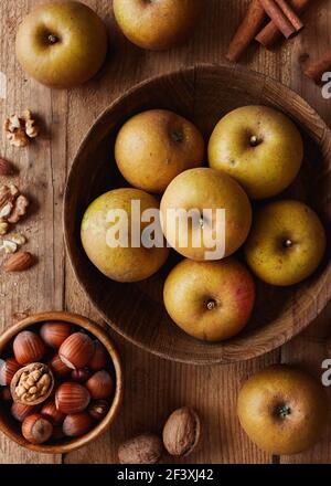 Autumn apples with nuts and cinnamon sticks on table, top view. Heirloom reinette apples. Stock Photo