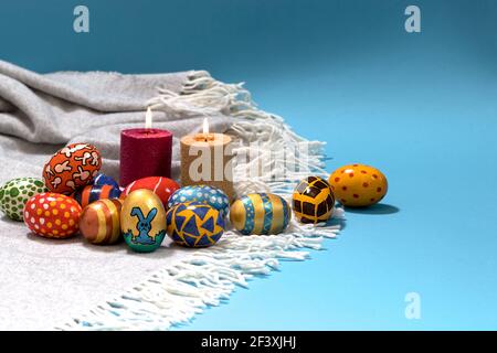 Festive religious photo of the Easter concept on a blue background with candles and painted eggs. Copy the space for text Stock Photo