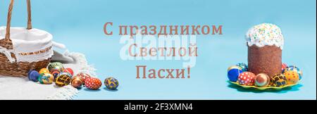 A congratulatory blue banner with an Easter cake, a basket and eggs with the inscription in Russian language Happy Easter Stock Photo