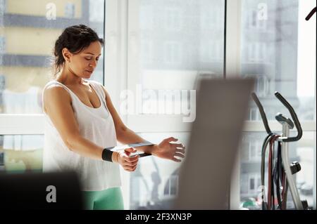 Side portrait of a young woman exercising with rubber elastic band at home. Workout, stretching, fitness at home Stock Photo