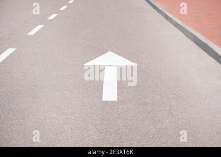 Forward signs on the road. White arrow marking pointing ahead on asphalt. Stock Photo