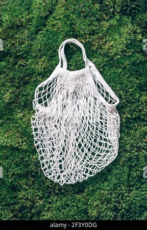 Reusable net bag or mesh shopper on green grass, moss background. Zero waste, plastic free concept. Top view. Eco friendly mesh shopper. Sustainable Stock Photo