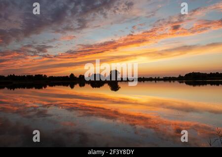 Wonderful colorful clouds reflected in the lake water after sunset, Stankow, Poland Stock Photo