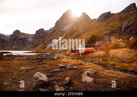 Hiking through a mountainous fjord landscape while the sun sets over the mountain peaks - landscape photo in autumn with a typical norwegian house - h Stock Photo