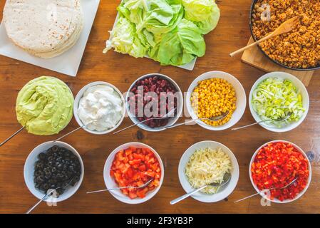 Mixed mexican food background. Party food. Guacamole, fajita, meat tacos, salsa, peppers, tomatoes on a wooden table. Stock Photo